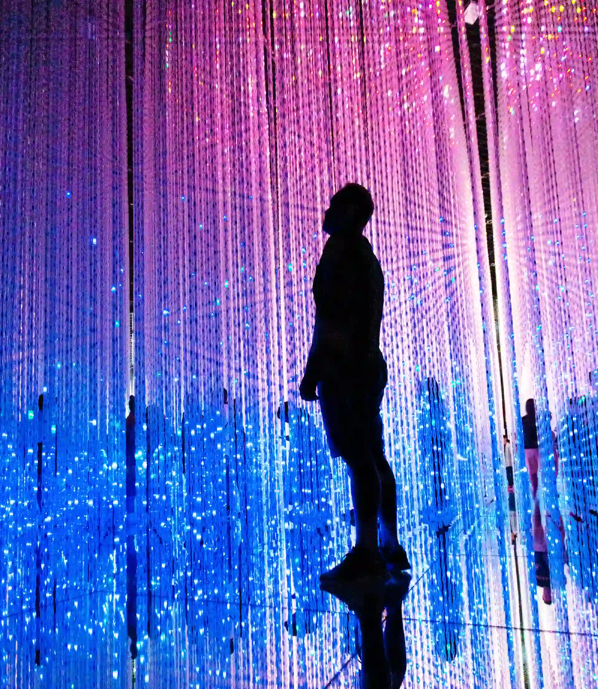 Un hombre de pie frente a una pantalla de luces coloridas.